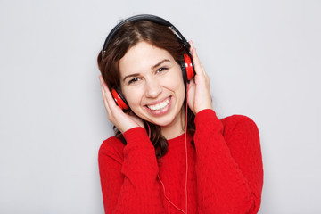 Close up young woman smiling with head phones by gray background