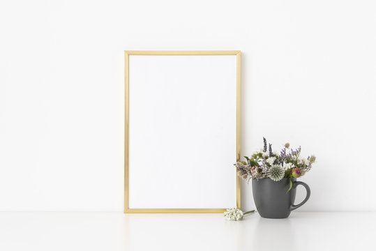 Gold a4 portrait frame mockup with small bouquet of dried flowers in pot on white wall background. Empty frame, poster mock up for presentation design. Template frame for text, lettering, modern art.