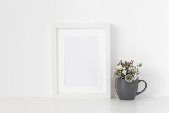 Modern white A5 portrait frame mockup with dried field wild flowers in pot on white wall background. Empty frame, poster mock up for presentation design. 
