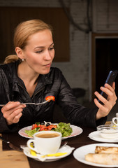 businesswoman eating salad in an outdoor cafe. Healthy lifestyle: girl eating green tasty food and checks email on your phone