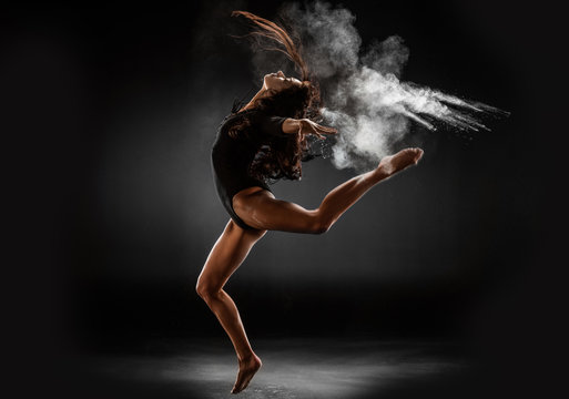 young ballerina in black bodysuit with talc powder dancing on dark background © LIGHTFIELD STUDIOS