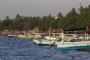 Colored fishing boats lie on the beach of lovina, during sunset on Bali.