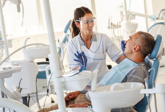 Dentist  in dental office talking with male patient and preparing for treatment.