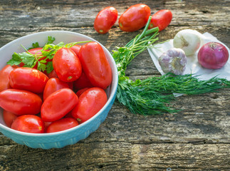 ripe tomatoes in bowl on wooden background