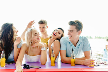 A company of good-looking friends laughing, drinking yellow cock