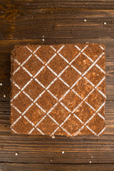 Dark chocolate vegan cake with candies and nuts on wooden background