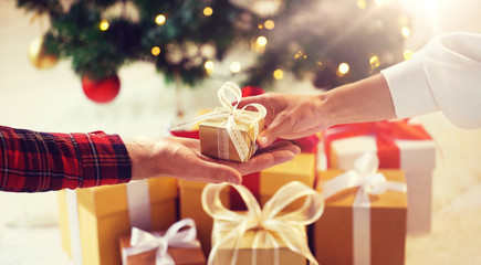 holidays, presents, new year and celebration concept - close up of couple hands giving and receiving christmas gift box