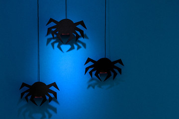 Black paper spider with web on dark blue background. Halloween concept. Paper cut style. Top view