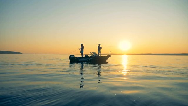 Fishing process of two male fishermen during sunrise