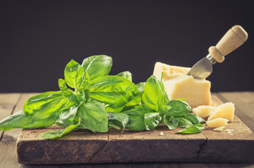 Parmesan and basil on rustic wood background.