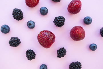 Flat lay of berries on pastel colored background.