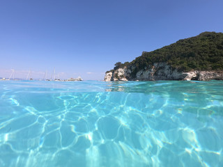 Fototapeta premium Underwater photo of tropical paradise turquoise exotic beach of Voutoumi with sail boats docked in island of Antipaxos, Ionian, Greece