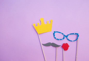 Photo booth props glasses, moustaches, crown and lips on pink background.
