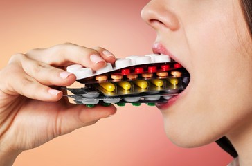 Girl eating lots of pills on background