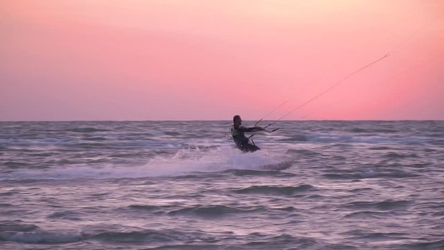 A man kiter at dawn bounces over the waves