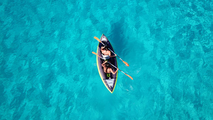 Aerial drone bird's eye view photo of 2 women canoeing in tropical beach of Voutoumi, Antipaxos island, Greece