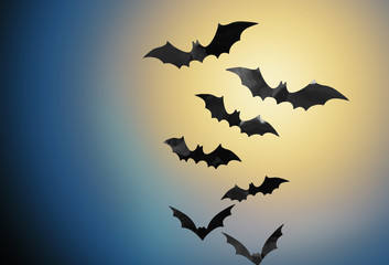 halloween and scary concept - black bats flying in moonlight over night sky background
