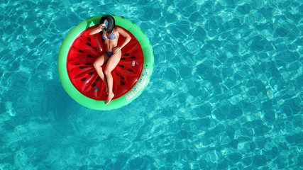 Aerial drone top photo of unidentified woman wearing a hat sitting in inflattalbe watermelon in tropical paradise beach resembling a pool