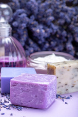 Obraz na płótnie Canvas Natural healthy aromatherapy and skin treatment with organic French lavender, lavender soap, face cream, essential oils on purple background with dried lavender flowers