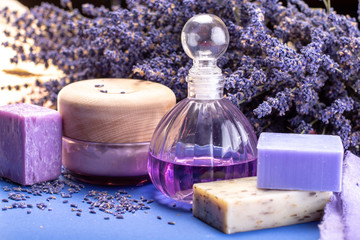 Obraz na płótnie Canvas Natural healthy aromatherapy and skin treatment with organic French lavender, lavender soap, body cream and essential oils on purple background with dried lavender flowers
