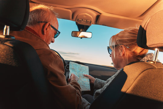 Elderly loving couple traveling in car on vacation. They are looking on a map for direction. - Powered by Adobe
