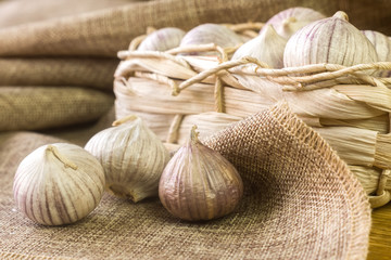 Garlic bulbs on the fabric next to the  basket.