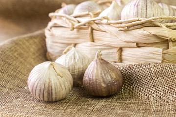 Garlic on the fabric next to the wicker basket.
