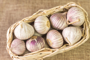 Wicker basket filled with garlic on a linen tablecloth, the view from the top.