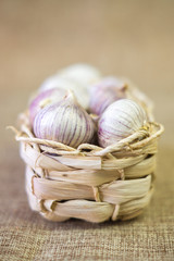Garlic  in a light wicker basket on a linen tablecloth.