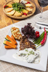 Modern style barbecue dry aged sliced roast beef with fried onion rings and mashed potatoes as closeup on a plate