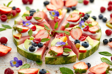 Watermelon pizza with various fresh fruits with the addition of cream cheese, mint and edible...