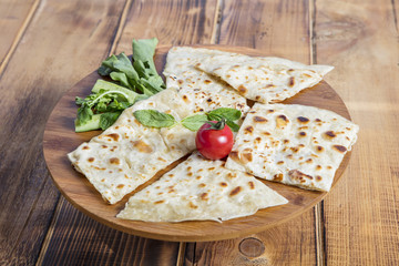Typical Turkish meal Gozleme with herb and cheese on light wooden cutting board.