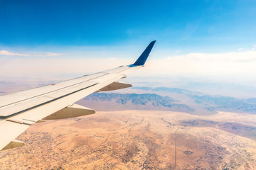 airplane wing over the desert city on sunny day.