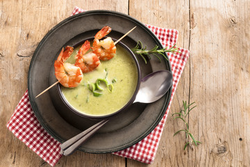 prawn skewers and leek cream soup on a rustic wooden table, top view from above with copy space