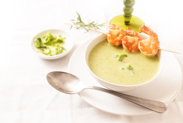 king prawns with green vegetable cream soup on a white tablecloth, copy space