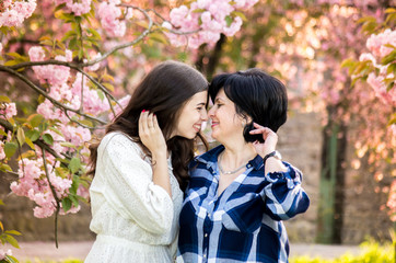 Mother with an adult daughter together in a blooming sakura park