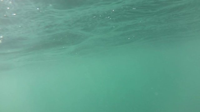 Hand of a swimmer under blue water near a surface with waves
