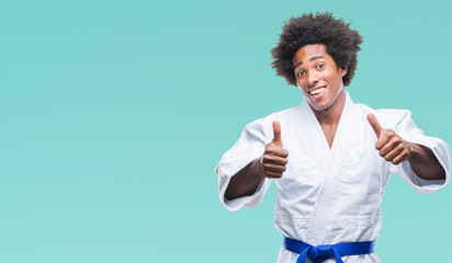 Afro american man wearing karate kimono over isolated background approving doing positive gesture with hand, thumbs up smiling and happy for success. Looking at the camera, winner gesture.