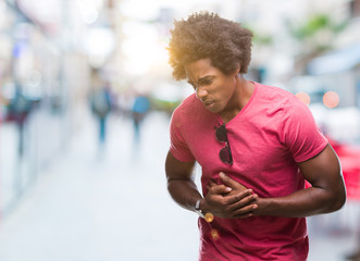 Afro american man over isolated background with hand on stomach because nausea, painful disease...