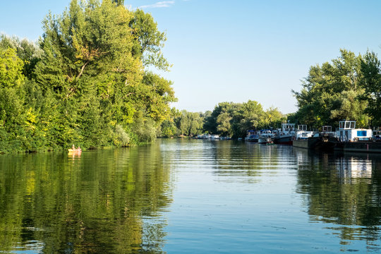 The sunny summer day on the picturesque banks of the Tisza river in Tokaj, Hungary - a beautiful countryside landscape with reed, boat and reflection on water mirror