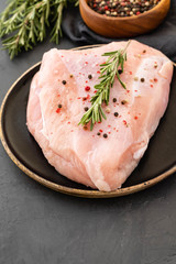 Turkey breast raw meat with spices on a dark background. Copy space.