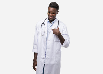 Young african american man wearing doctor coat with surprise face pointing finger to himself