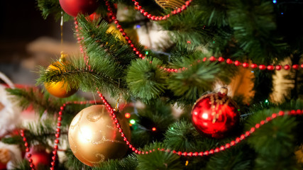 Obraz na płótnie Canvas CLoseup photo of golden and red baubles hanging on beautiful Christmas tree