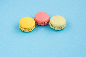 Macaroons, pink, yellow and green macaroons on blue background