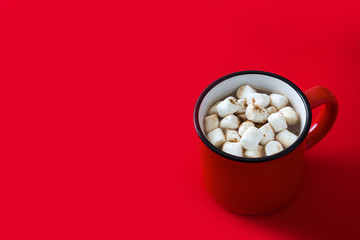 Christmas cocoa with marshmallow in mug on red background. Copyspace