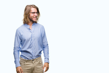 Fototapeta premium Young handsome man with long hair wearing glasses over isolated background looking away to side with smile on face, natural expression. Laughing confident.