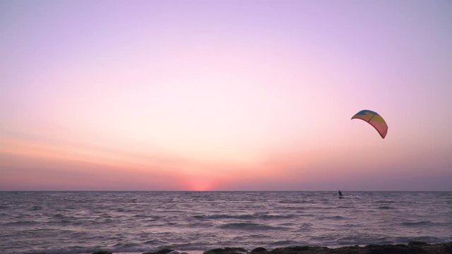 A man controls a training kite, alone kitesurfer at dawn, slow motion