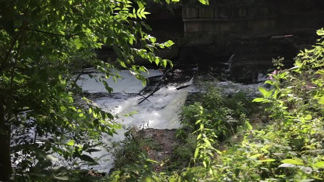 A small waterfall on the Sestra river in Klin through the branches of the trees