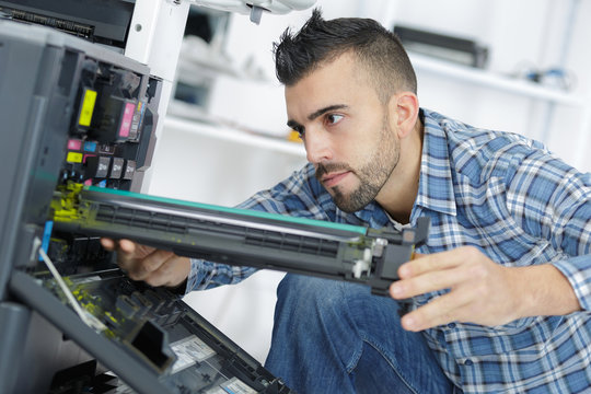 young man repairing printer in modern office