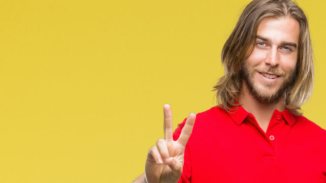 Young handsome man with long hair over isolated background smiling looking to the camera showing fingers doing victory sign. Number two.